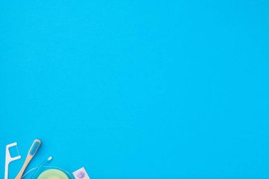 Diş fırçaları ve oral bakım araçları mavi arka plan üst görünüm fotokopi alanı düzlüğü üzerinde. Diş bakımı, diş hijyeni ve sağlık konsepti. 