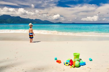 Üç yaşında bir çocuk sahilde plaj oyuncaklarıyla oynuyor. Seyşeller 'de yaz tatili, Mahe..