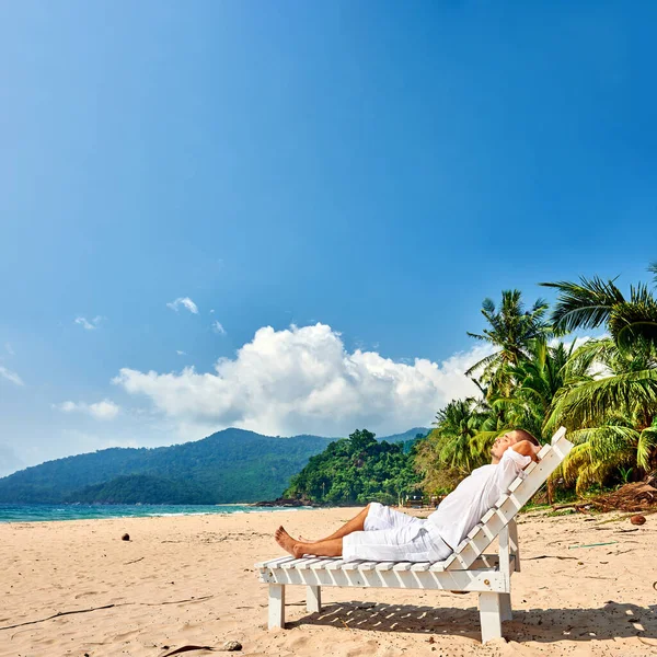 马来西亚蒂奥曼岛的一个热带海滩上 一个白衣男子躺在日光浴床上休息 — 图库照片