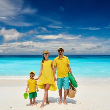 Petite Anse plajında güzel bir aile, üç yaşında bir çocukla sarı elbiseli genç bir çift. Seyşeller 'de yaz tatili, Mahe..