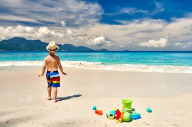 Üç yaşında bir çocuk sahilde plaj oyuncaklarıyla oynuyor. Seyşeller 'de yaz tatili, Mahe..