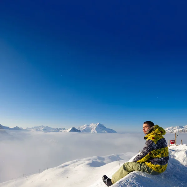 Paisaje Alpino Montaña Invierno Con Hombre Sentado Sobre Nubes Bajas —  Fotos de Stock