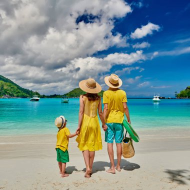 Sahilde bir aile, sarı elbiseli genç bir çift ve üç yaşında bir çocuk. Seyşeller 'de yaz tatili. Port Launay, Mahe. 