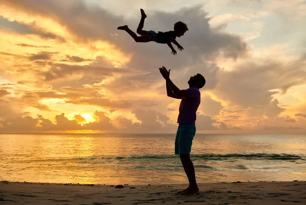 快乐快乐的孩子 父亲把儿子抛向空中 3岁的幼儿日落时与父亲在海滩上玩耍 在塞舌尔马埃岛的夏季家庭度假 — 图库照片