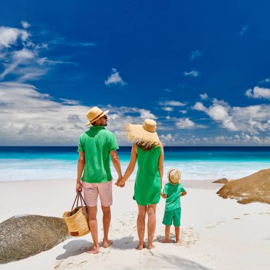 Güzel Anse Intendance plajında bir aile, yeşil elbiseli genç bir çift ve üç yaşında bir çocuk. Seyşeller 'de yaz tatili, Mahe..