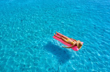 Plajda şişme minder üzerinde dinlenen bir kadın.