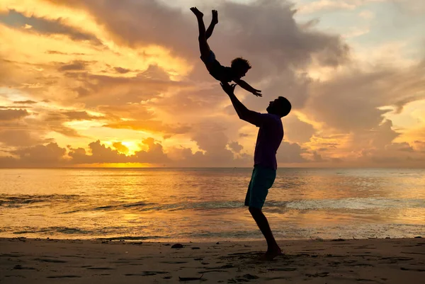快乐快乐的孩子 父亲把儿子抛向空中 3岁的幼儿日落时与父亲在海滩上玩耍 在塞舌尔马埃岛的夏季家庭度假 — 图库照片