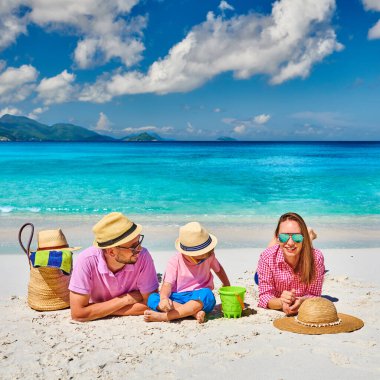 Güzel Anse Soleil plajında bir aile, üç yaşında bir çocuğu olan genç bir çift. Seyşeller 'de yaz tatili, Mahe..