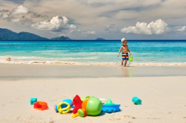 Üç yaşında bir çocuk sahilde plaj oyuncaklarıyla oynuyor. Seyşeller 'de yaz tatili, Mahe..