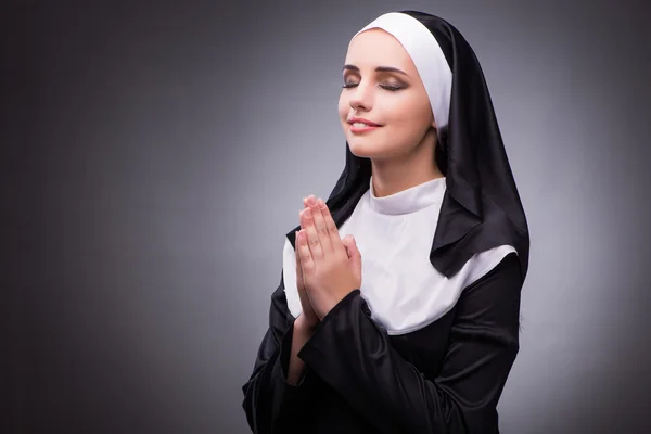 Religieuze nun in religie concept tegen de donkere achtergrond — Stockfoto