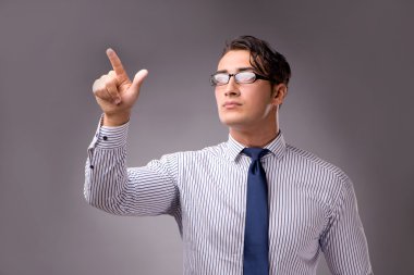 Genç yakışıklı işadamı düğmelere basarak gri arka plan üzerinde