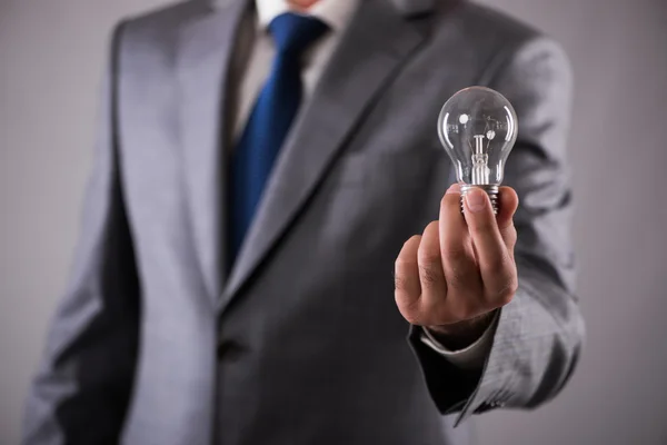 Podnikatel, drží žárovku v pojetí kreativity — Stock fotografie