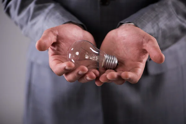 Businessman holding light bulb in creativity concept — Stock Photo, Image