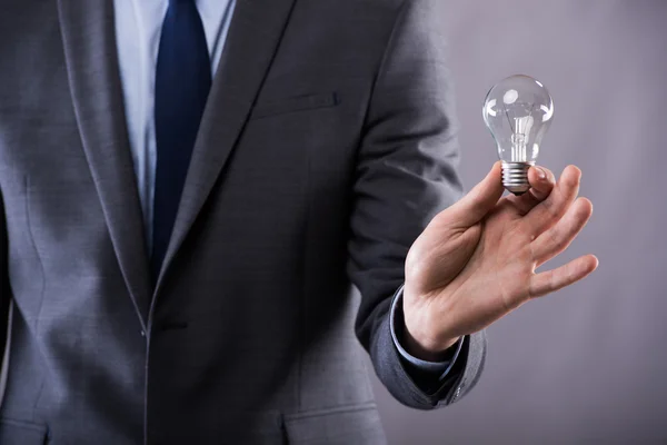 Podnikatel, drží žárovku v pojetí kreativity — Stock fotografie