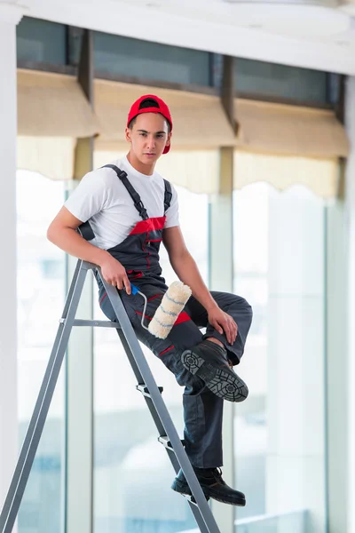 Jovem pintor pintando o teto no conceito de construção — Fotografia de Stock