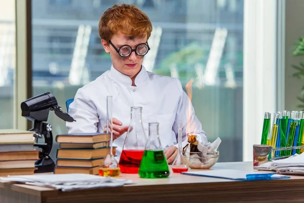 Молодой сумасшедший химик работает в лаборатории — стоковое фото