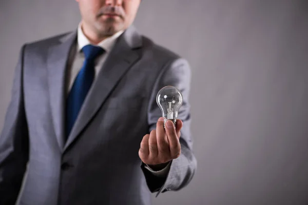 Businessman holding light bulb in creativity concept — Stock Photo, Image