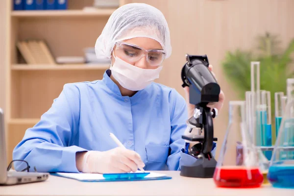 Químico de laboratório trabalhando com microscópio e tubos — Fotografia de Stock