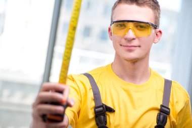 Sarı tulumlu genç inşaat işçisi.