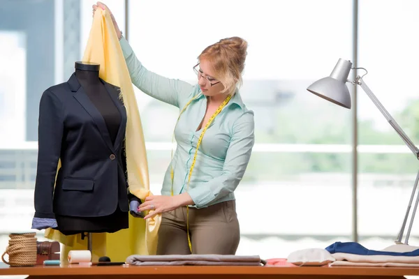 Mulher alfaiate trabalhando em roupas novas — Fotografia de Stock