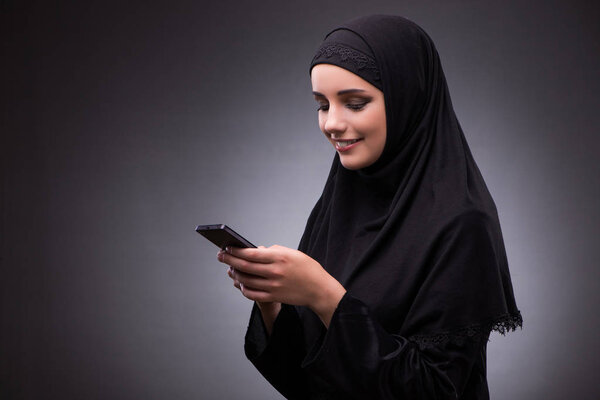 Muslim woman in black dress against dark background