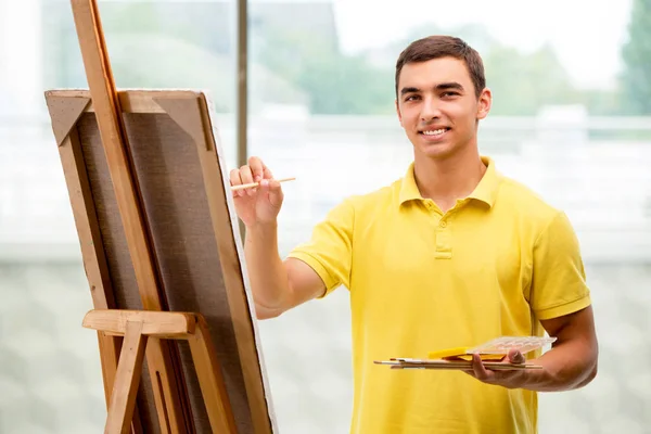 Jonge mannelijke kunstenaar tekening foto 's in heldere studio — Stockfoto