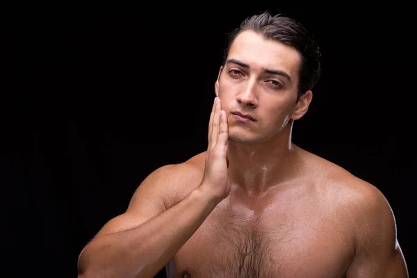 Man na het nemen van douche op donkere achtergrond — Stockfoto