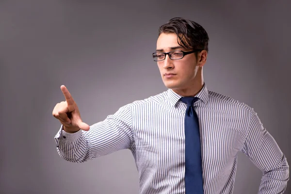 Jonge knappe zakenman knoppen in te drukken op een grijze achtergrond — Stockfoto