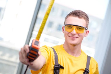 Sarı tulumlu genç inşaat işçisi.