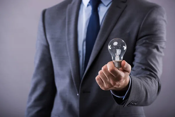 Businessman holding light bulb in creativity concept — Stock Photo, Image