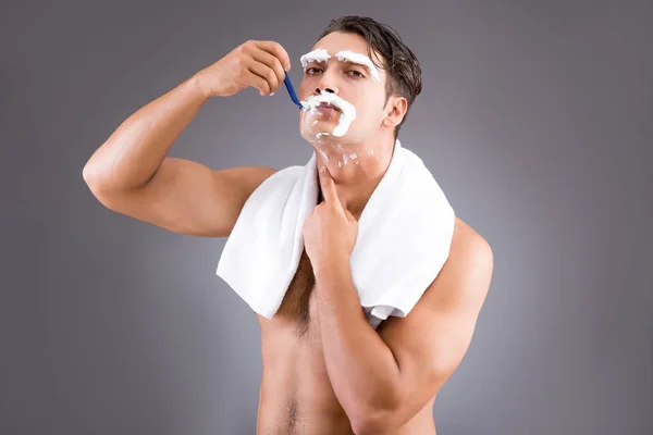 Handsome man shaving against dark background — Stock Photo, Image