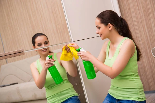 Jeune femme nettoyage miroir à la maison — Photo