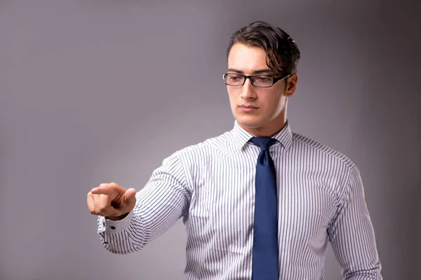 Junger gutaussehender Geschäftsmann drückt Knöpfe auf grauem Hintergrund — Stockfoto