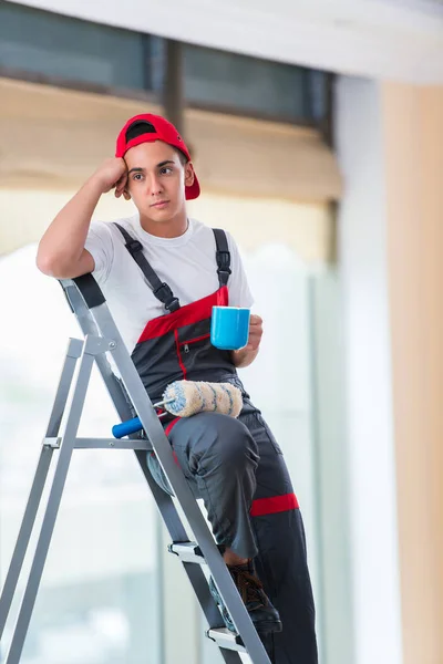 Jovem pintor pintando o teto no conceito de construção — Fotografia de Stock