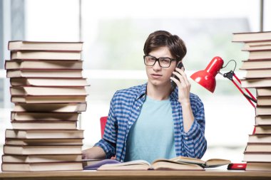 Bir sürü kitabı olan öğrenci sınavlara hazırlanıyor.