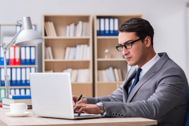 Genç yakışıklı işadamı ofiste çalışıyor.