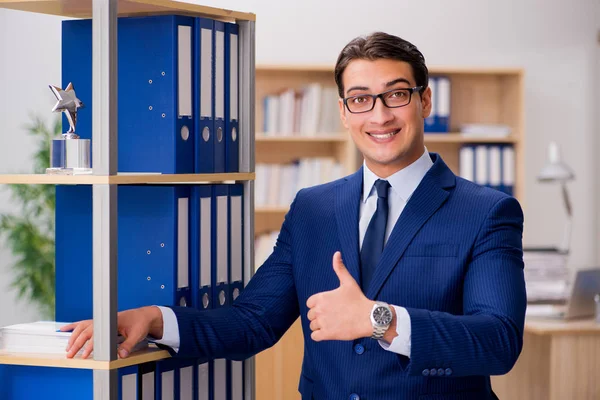 Hombre de negocios guapo de pie junto a la estantería —  Fotos de Stock