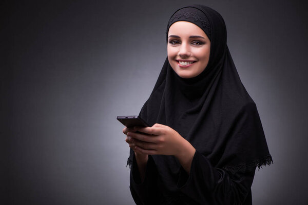 Muslim woman in black dress against dark background