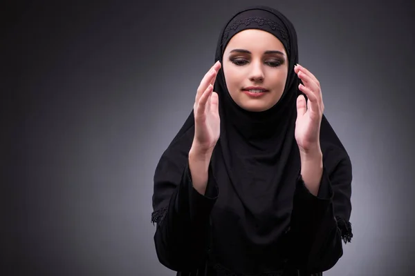 Donna musulmana in abito nero contro sfondo scuro — Foto Stock