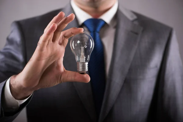 Businessman holding light bulb in creativity concept — Stock Photo, Image