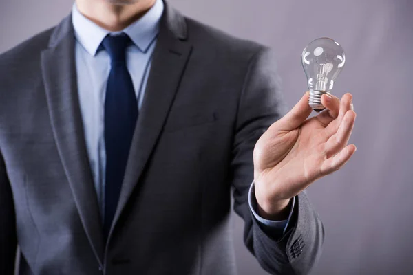 Businessman holding light bulb in creativity concept — Stock Photo, Image