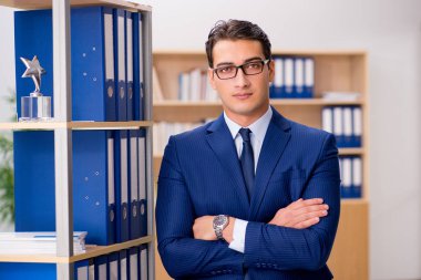 Yakışıklı işadamı raf yanında ayakta