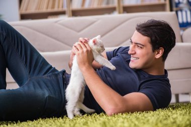 Yakışıklı delikanlı beyaz yavru kedi ile oynarken