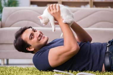 Yakışıklı delikanlı beyaz yavru kedi ile oynarken