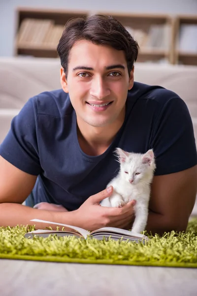 Junger schöner Mann spielt mit weißem Kätzchen — Stockfoto