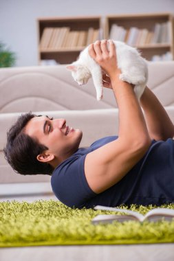 Yakışıklı delikanlı beyaz yavru kedi ile oynarken