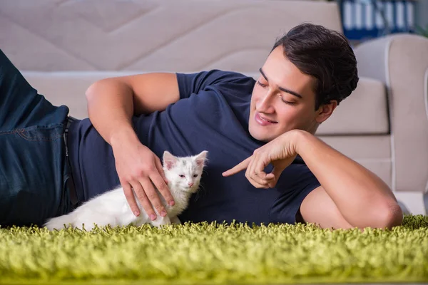 Jovem homem bonito brincando com gatinho branco — Fotografia de Stock