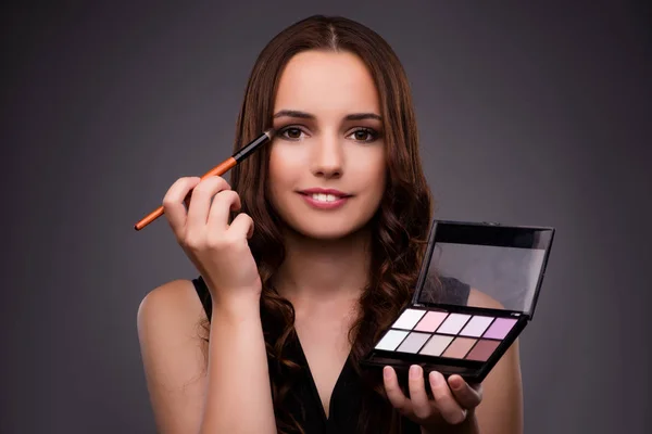 Mujer haciendo maquillaje sobre fondo oscuro — Foto de Stock