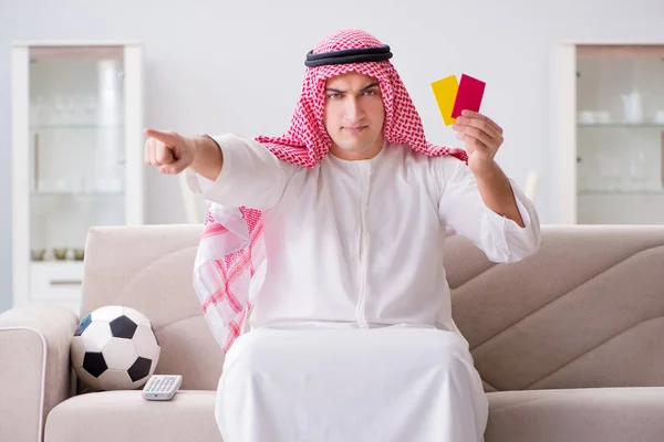 Young arab man watching football sitting on sofa — Stock Photo, Image