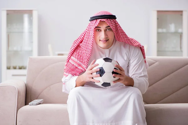 Hombre árabe joven viendo fútbol sentado en el sofá — Foto de Stock